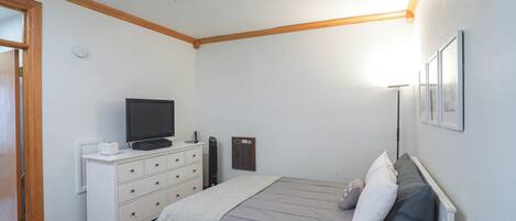 Ein Schlafzimmer mit einem Bett, einem Schminktisch, einem Fernseher und einer Heizung.