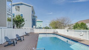 A swimming pool with a wooden deck, lounge chairs, and a white fence. - Steps to Ocean: Water-view Carolina Beach Unit! (Carolina Beach)