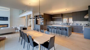 Een moderne keuken met een centraal eiland, inbouwapparatuur en een eethoek met een grote tafel en stoelen.