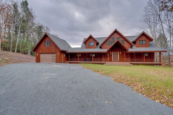 A large, multi-story wooden cabin with a spacious driveway and a well-maintained lawn.