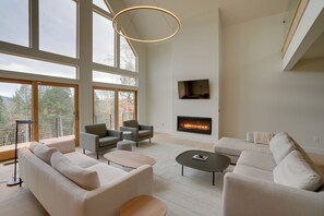 A spacious living room with large windows, a fireplace, and modern furniture.