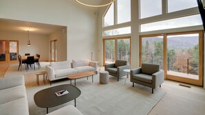 Een ruime woonkamer met een modern design, met een grote bank, een salontafel en een eethoek met een tafel en stoelen.