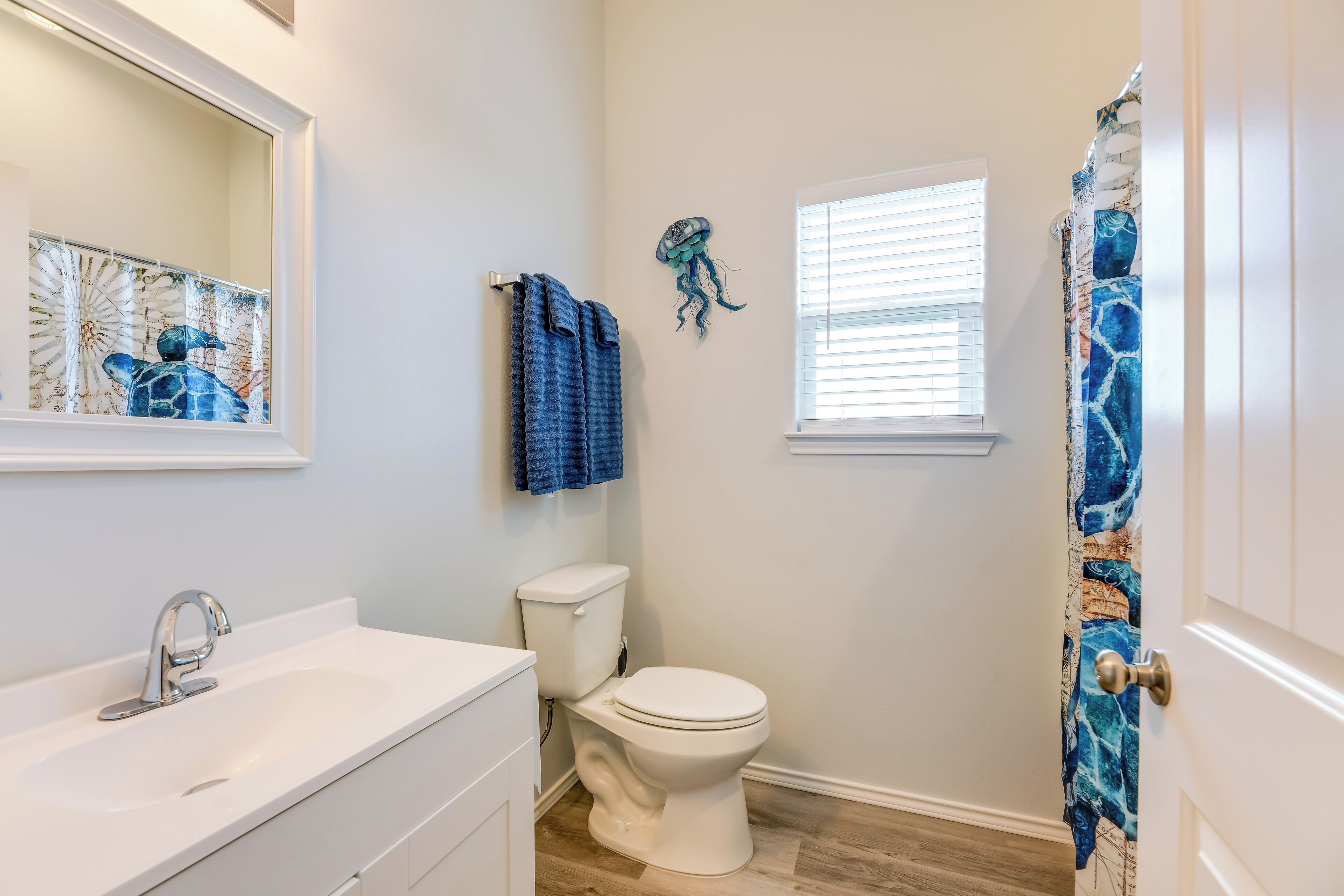 A bathroom with a white sink, a toilet, and a shower curtain with a blue pattern.