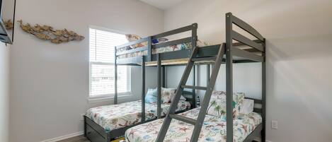 Un dormitorio con literas, ventilador de techo, ventana con persianas y un adorno de pared.