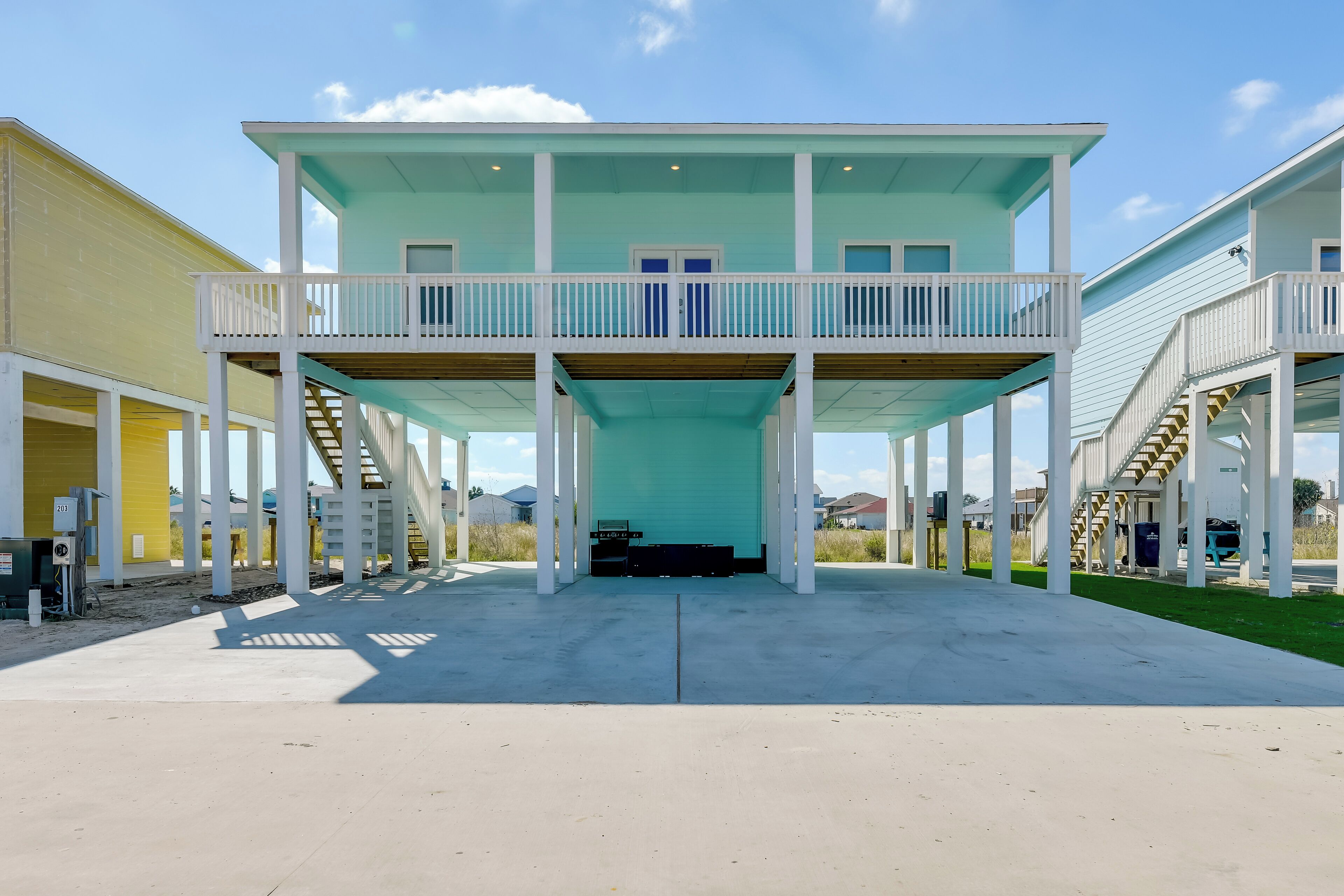 A two-story building with a balcony on the upper floor, a covered entrance, and a concrete driveway.