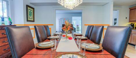Comedor con una mesa de madera dispuesta para seis personas, rodeada de sillas de cuero, un candelabro y un florero con flores.