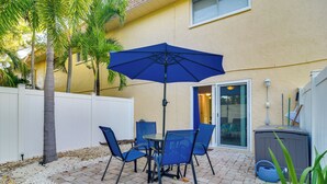 A patio with a table and chairs, a blue umbrella, and a white fence. - Near Beach! Modern Ground-floor Condo in St Pete (St. Pete Beach)