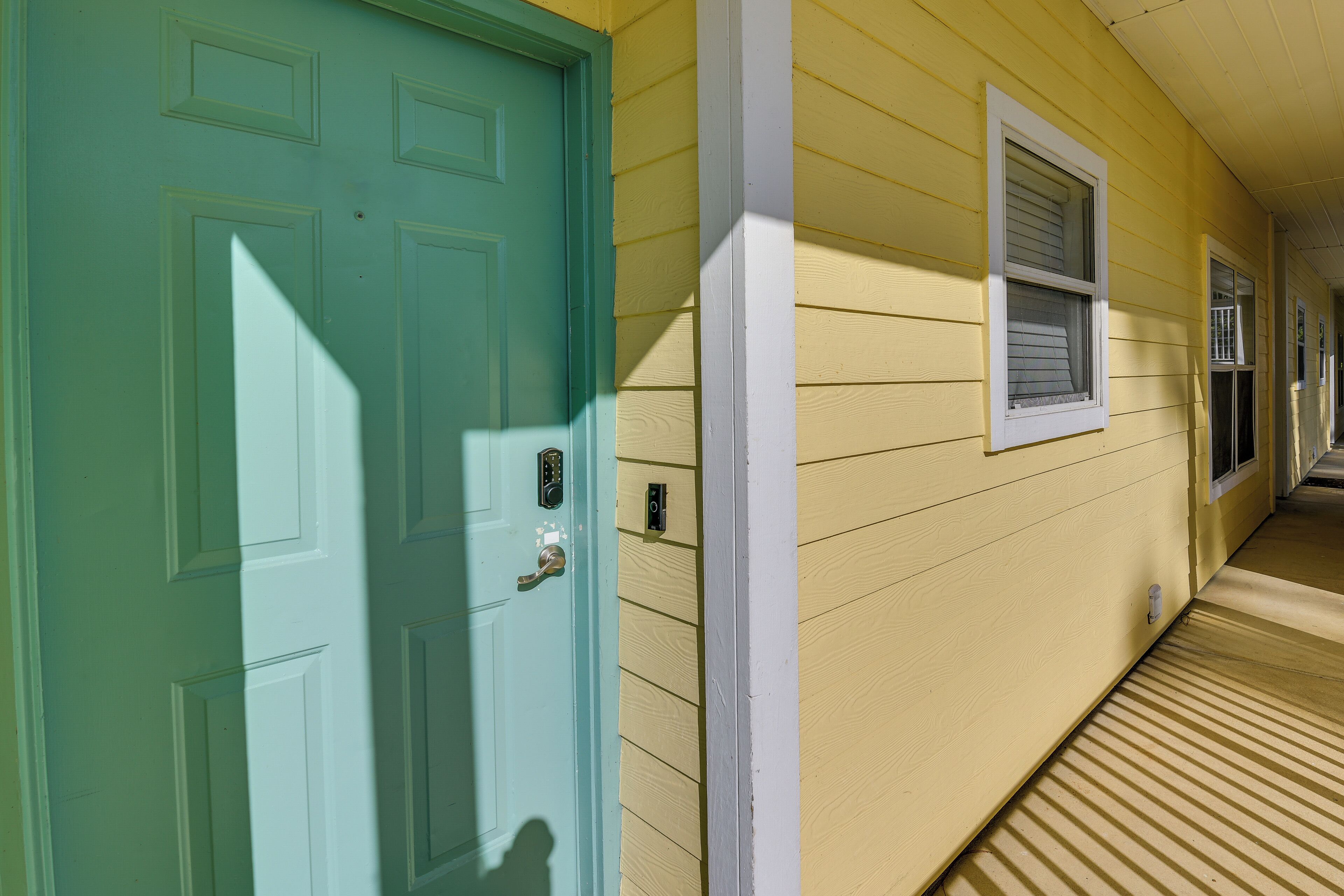 A hallway with a teal door and a yellow exterior wall.