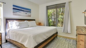 A bedroom with a wooden bed, white bedding, a large window with curtains, and a painting on the wall. - Prime Miramar Beach Getaway w/ Pool Access! (Miramar Beach)