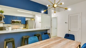 A modern kitchen with blue cabinets, a wooden dining table, and blue chairs. - Prime Miramar Beach Getaway w/ Pool Access! (Miramar Beach)