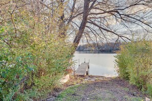 A wooden dock extending into a calm lake, surrounded by dense foliage.
