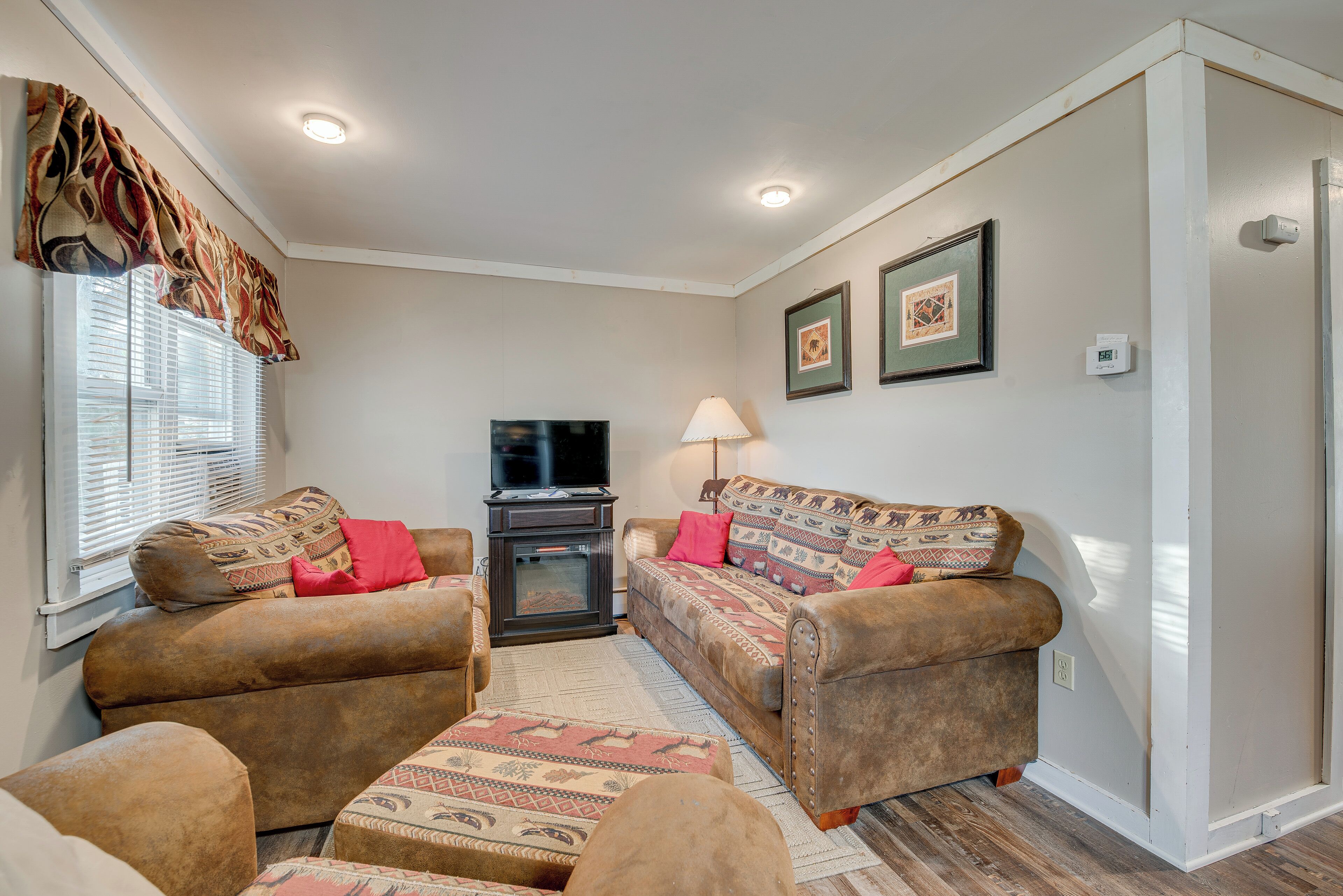 A living room with a sofa set, a television, a fireplace, and a lamp.