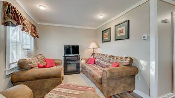 A living room with a sofa set, a television, a fireplace, and a lamp.