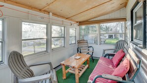 A room with a wooden ceiling, large windows, a wooden table, and a bench with cushions. - Cozy Pennsylvania Home w/ Fire Pit & Dock Access! (Carbondale)