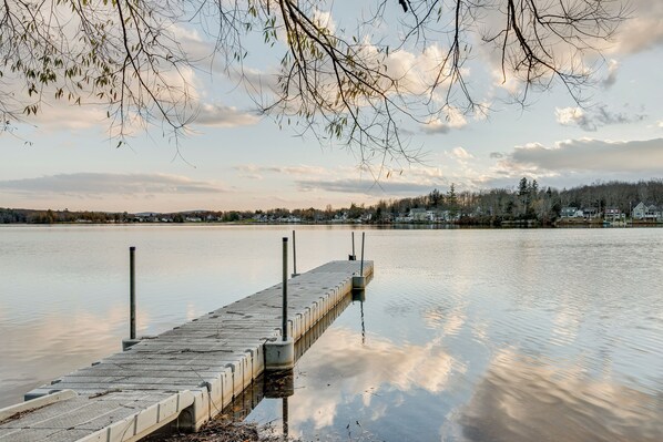 A wooden dock extending into a calm lake with a town in the background.