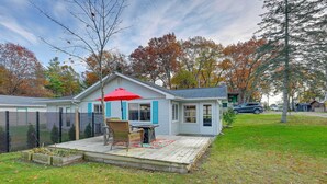 A house with a wooden deck, a red umbrella, and a small garden area. - Lovely Au Gres Cottage w/ Hot Tub: Walk to Beach! (Au Gres)