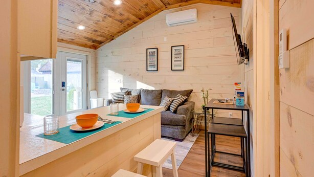 A cozy kitchen with a wooden ceiling, a bar area, and a grey sofa. - Lovely Au Gres Cottage w/ Hot Tub: Walk to Beach! (Au Gres)