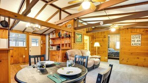 Uma área de refeições acolhedora com uma mesa de madeira, cadeiras e um ventilador de teto.