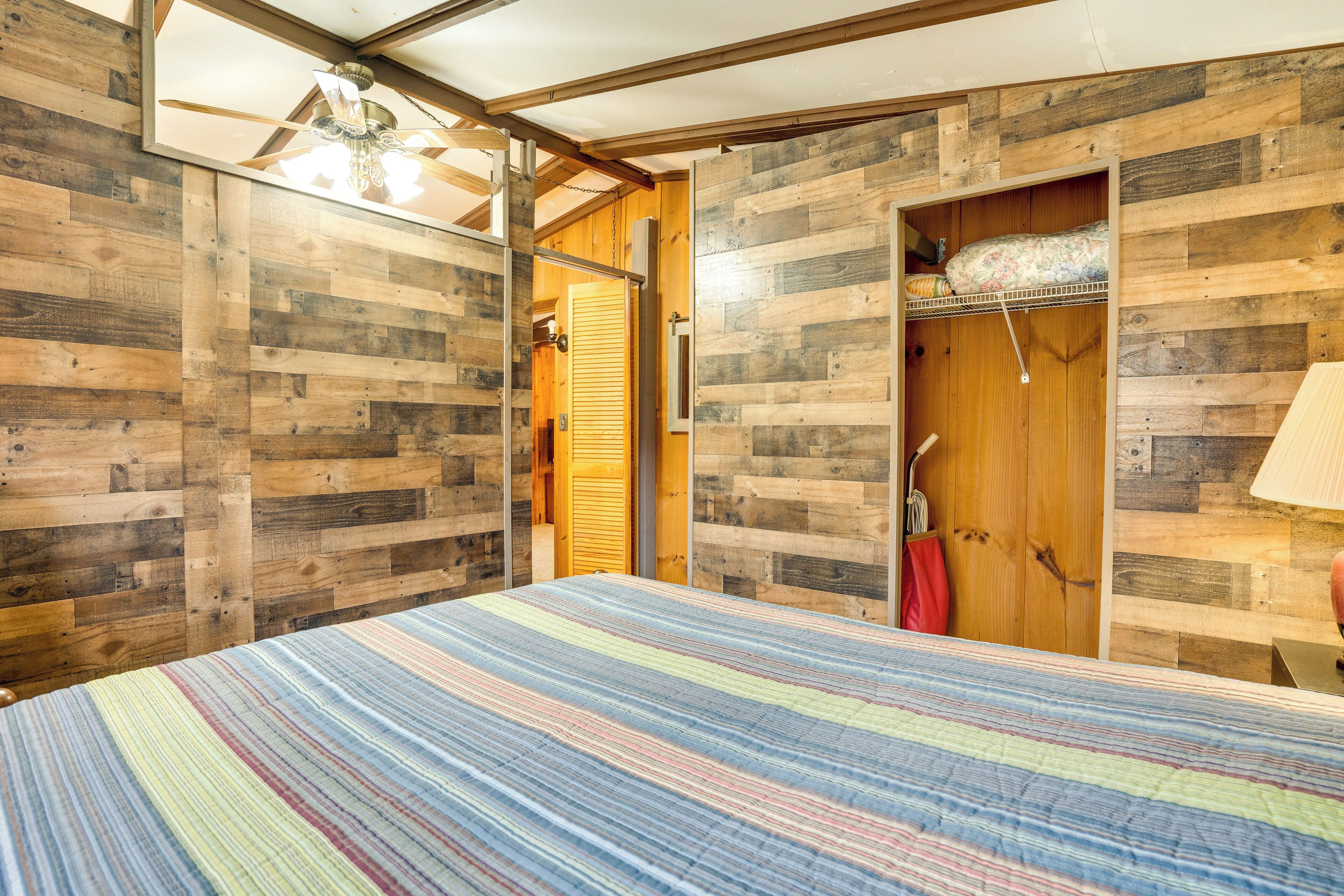 Un dormitorio con cama, paredes de madera, un armario y ventilador de techo.