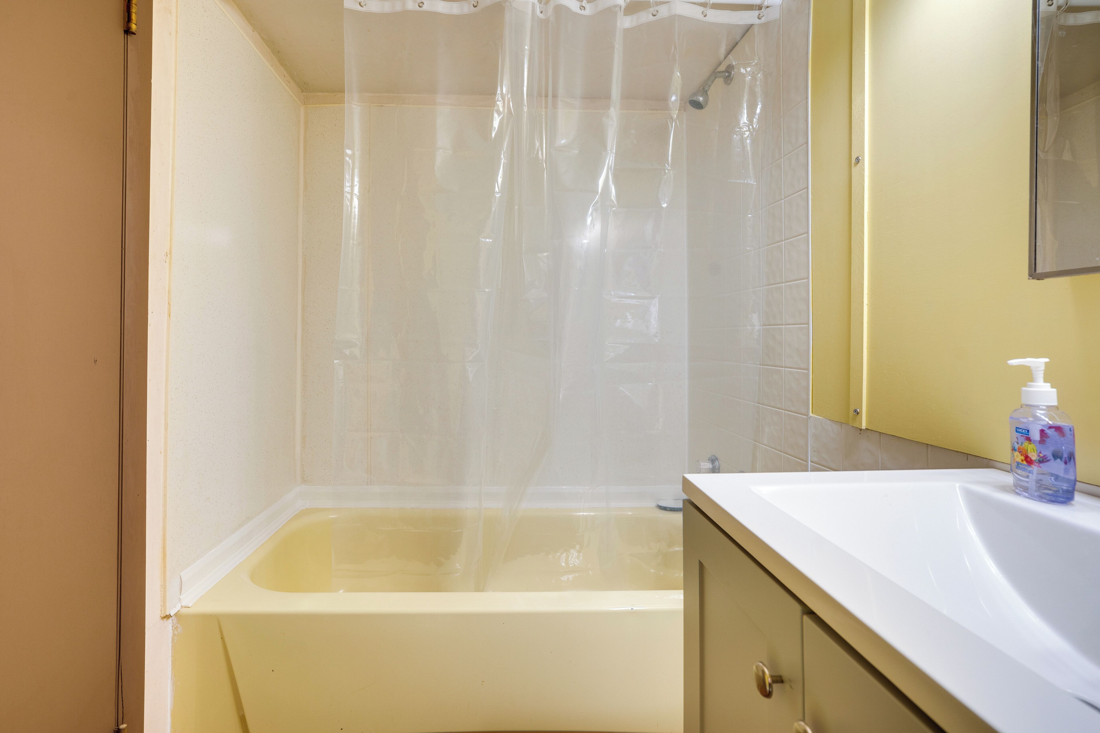 Un baño con bañera, cortina de ducha, lavabo y espejo.