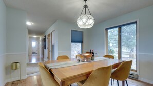 Un comedor con una mesa de madera, sillas amarillas y una lámpara colgante de diseño geométrico.