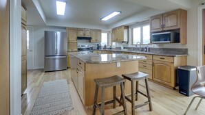 Una cocina amplia con armarios de madera, electrodomésticos de acero inoxidable y una isla central con taburetes.
