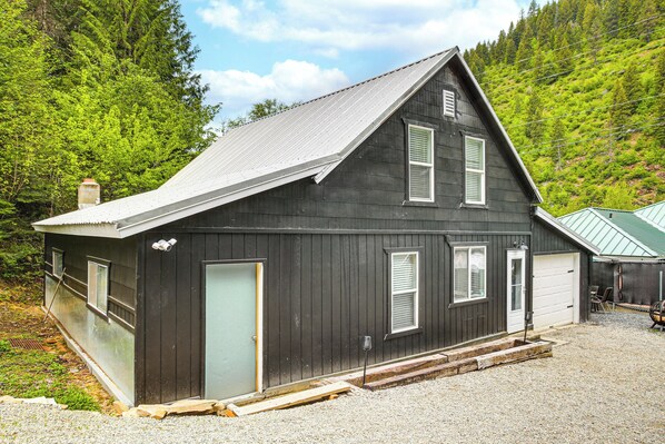 Ein zweistöckiges Holzhaus mit Metalldach, einer Haustür und einer Garage.