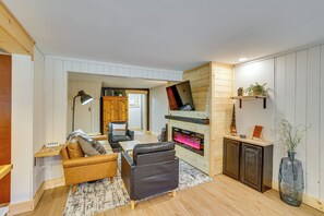 Ein gemütliches Wohnzimmer mit Kamin, Sofa, Couchtisch und einer Lampe.