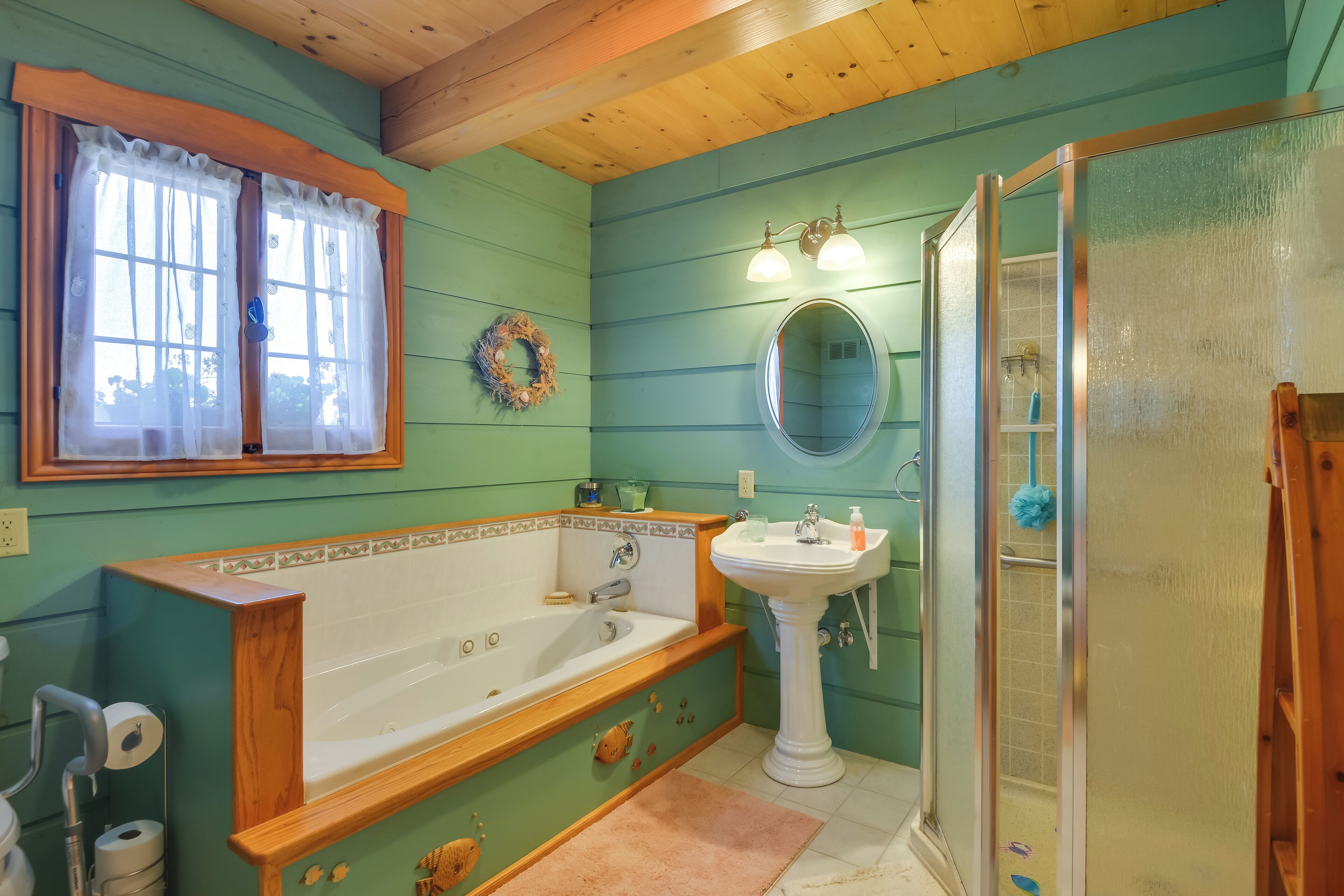 Ein Badezimmer mit einer Holzbadewanne, einem Standwaschbecken, einer Duschkabine aus Glas und einem Fenster mit Vorhängen.