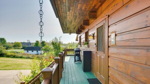 Eine Holzterrasse mit grünem Boden, einem Grill und einem Mülleimer.