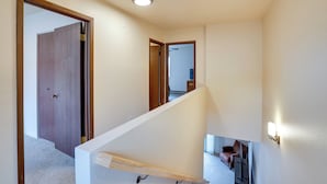 Una escalera con barandilla, una puerta de madera y un aplique en la pared.