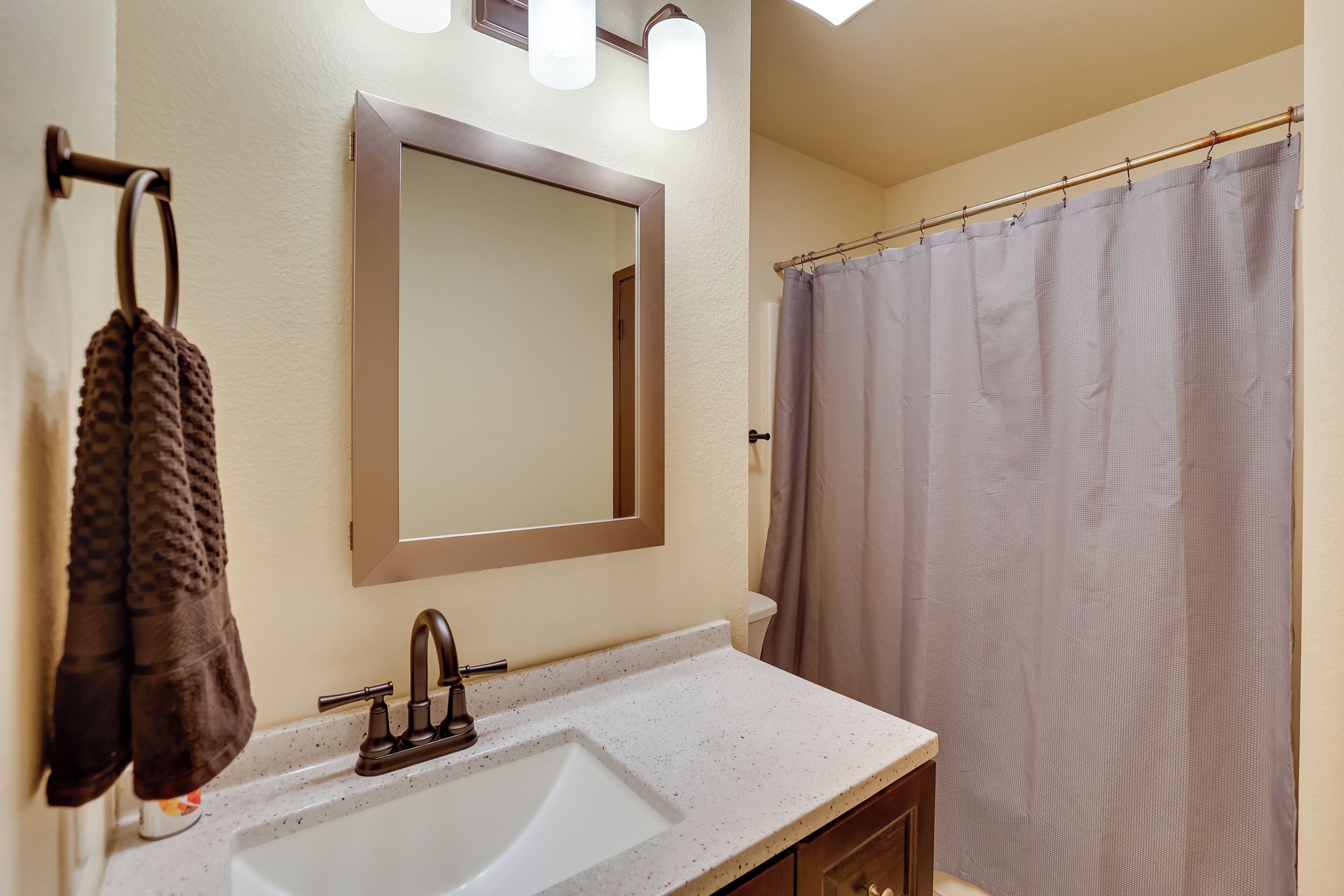 A bathroom with a white sink, a mirror, and a shower curtain.