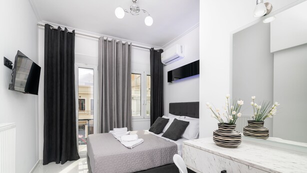 A modern bedroom with a bed, bedside table, and a large mirror. - Jensila Suite (Zakynthos)