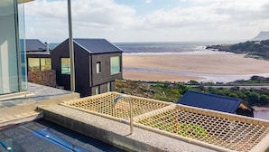 A modern building with a pool area overlooking a beach. - Hytte Riverview (Rooiels)