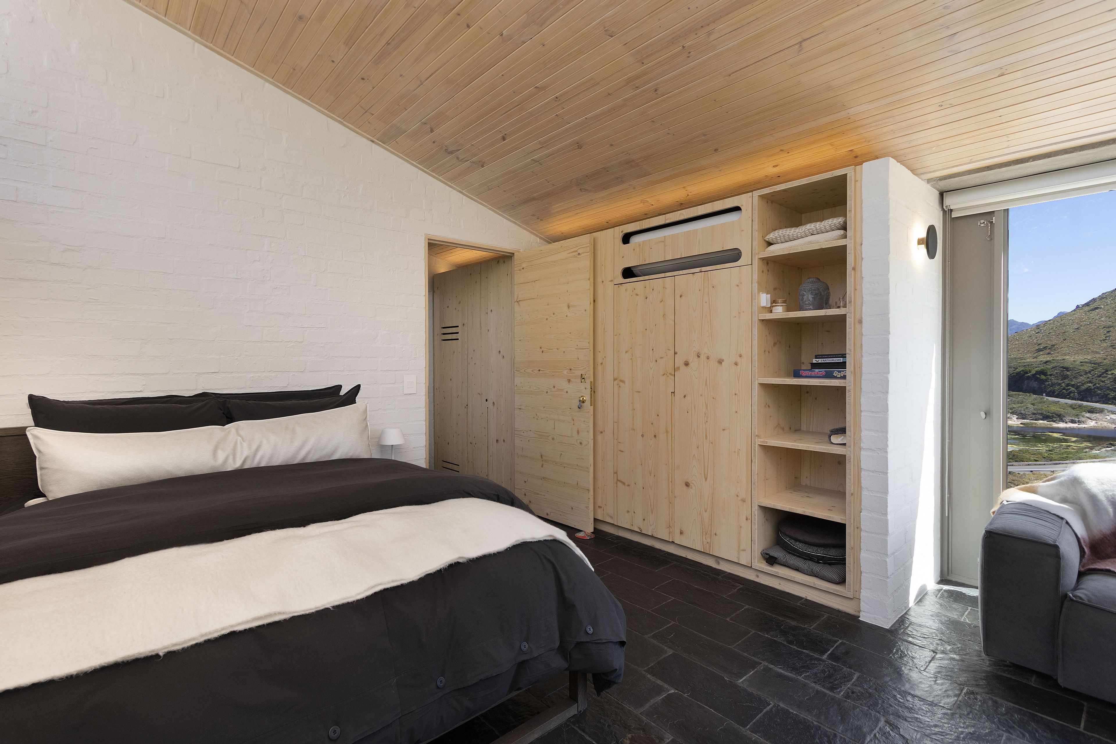 Un dormitorio con cama, armario y vistas al exterior.