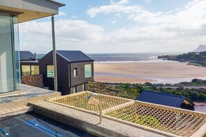A modern building with a pool area overlooking a beach. - Hytte Riverview (Rooiels)