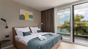 Un dormitorio moderno con una cama grande, un cuadro en la pared y vistas a través de una puerta corrediza de vidrio.