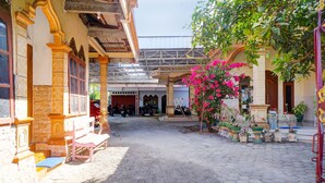 A courtyard with a covered seating area, potted plants, and a building entrance. - OYO Life 92918 Rumah Kost Arrahma Syariah (Lengkong)