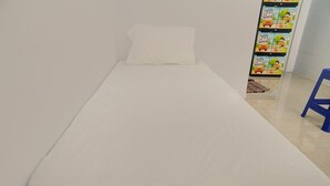 A single-bed room with a white mattress and pillow, a blue chair, and a colorful wall mural. - OYO Life 92918 Rumah Kost Arrahma Syariah (Lengkong)