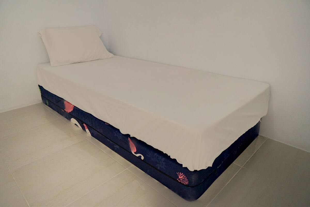 Ein kleines Bett mit weißer Matratze und blauer Basis mit floralem Muster.