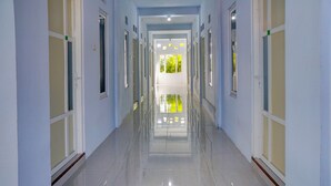 A long, narrow hallway with white walls and doors on both sides. - OYO Life 92918 Rumah Kost Arrahma Syariah (Lengkong)