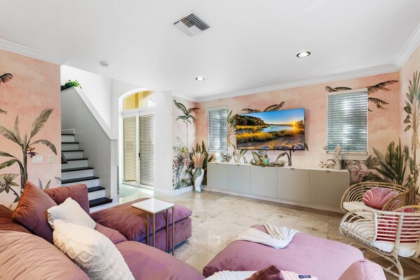 A modern living room with a staircase, a large painting, and tropical decor. - Welcome to The Betty!

 (Fort Lauderdale)