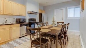 A modern kitchen with wooden cabinets, a dining table with chairs, and a large window providing natural light. - NEW! Boston Condo Near MBTA, 3Mi to Fenway! (U1) (Boston)