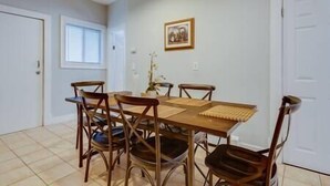 A dining area with a wooden table and chairs, a framed picture on the wall, and a door on the right. - NEW! Boston Condo Near MBTA, 3Mi to Fenway! (U1) (Boston)