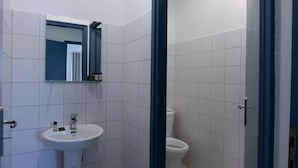 A bathroom with a white sink, a mirror, and a toilet. - Phaedrus Living Heraklion City View Flat (Heraklion)