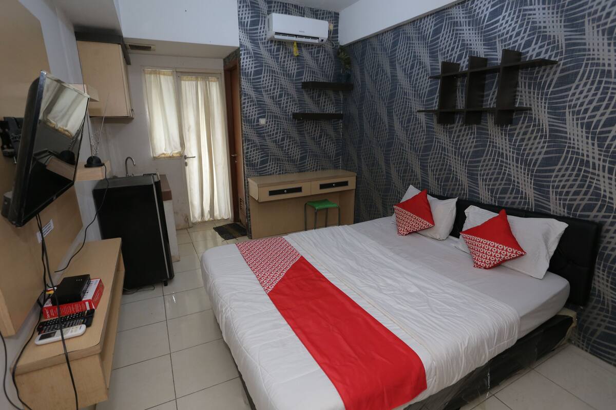 Een hotelkamer met een groot bed, een bureau met een computer, een televisie en een kledingkast.