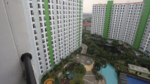 A high-rise residential building with multiple balconies, a central courtyard with a swimming pool, and surrounding greenery. - OYO Life 93008 Pelangi Coliving (Tangerang)
