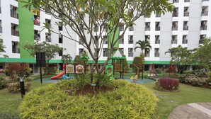 A playground with slides and swings, surrounded by well-maintained grass and plants. - OYO Life 93008 Pelangi Coliving (Tangerang)