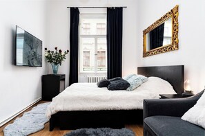 Une chambre moderne avec un lit, une table de chevet, un miroir et une fenêtre avec des rideaux.