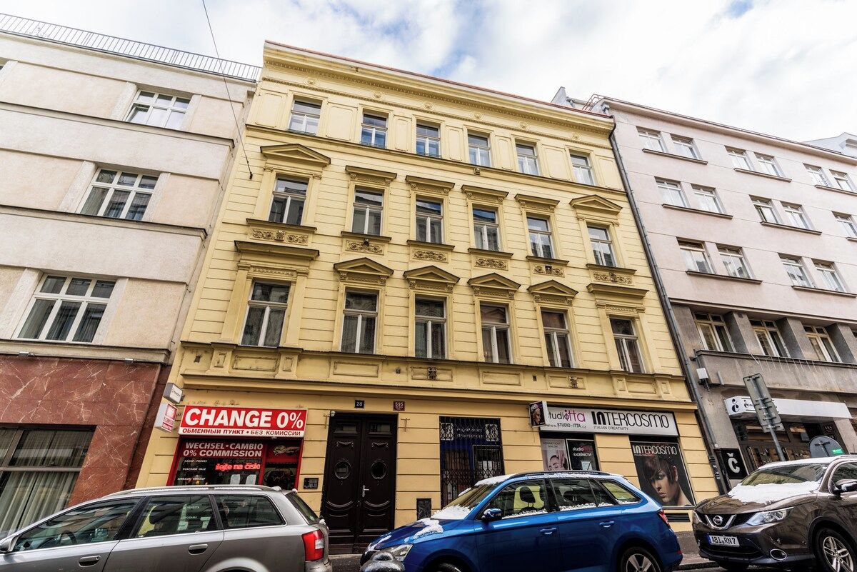 A multi-story building with a prominent yellow facade, a black door entrance, and a sign for a change of currency exchange service.